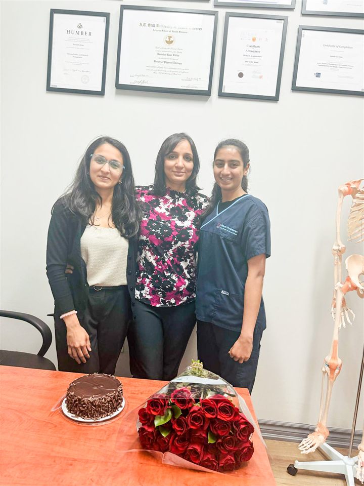 Ravinder Kaur Sidhu at Circle Physiotherapy with members of her clinical team, her degrees and certifications framed on the wall behind her